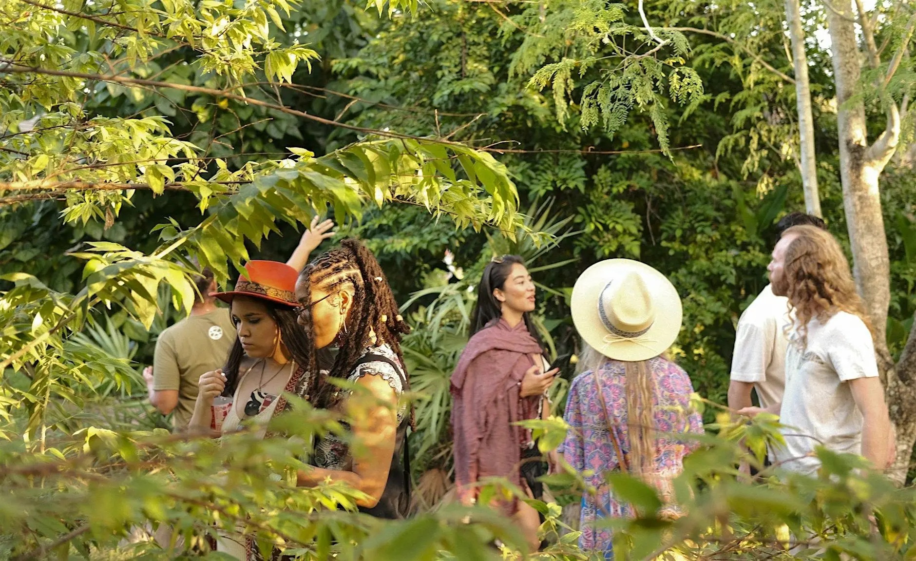 People gathering informally in a lush outdoor space.